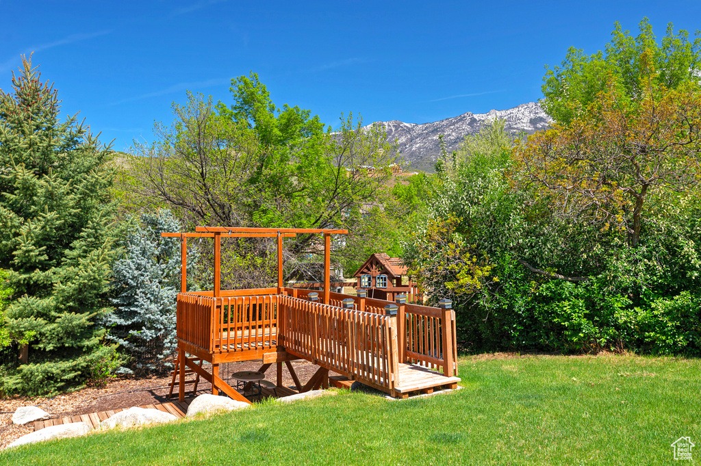 View of green lawn featuring a deck with mountain view