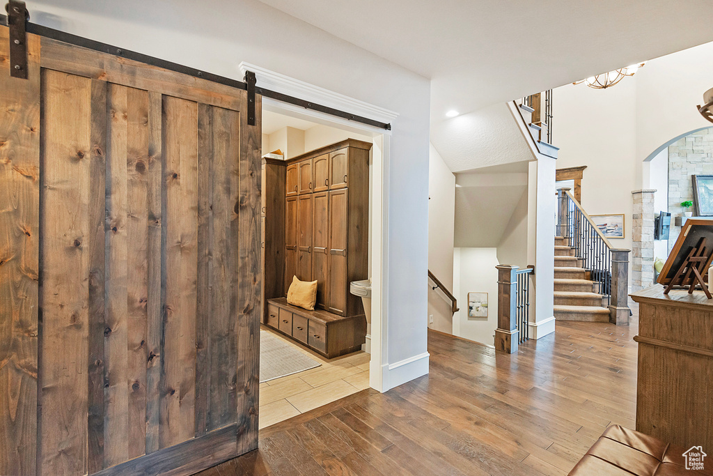 Entrance foyer featuring wood-type flooring, arched walkways, a barn door, stairs, and recessed lighting