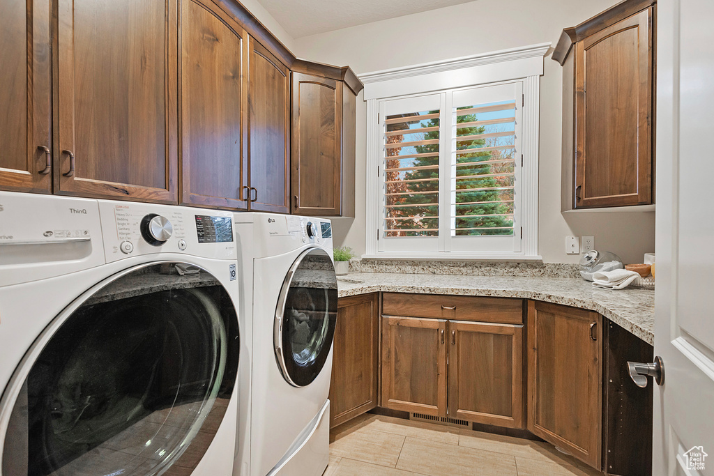 Washroom featuring cabinet space, separate washer and dryer, and light tile patterned floors