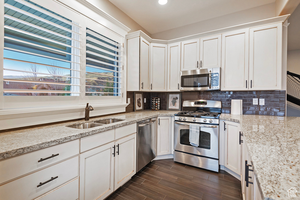 Kitchen featuring appliances with stainless steel finishes, a sink, tasteful backsplash, white cabinetry, and recessed lighting