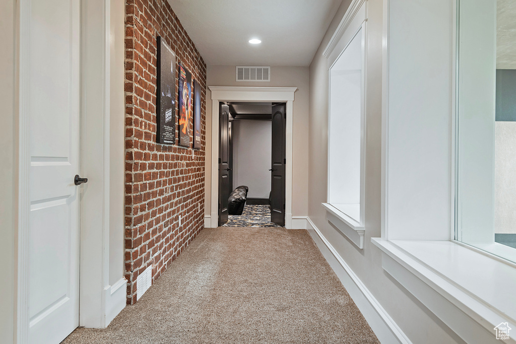 Hall featuring brick wall, carpet floors, and baseboards