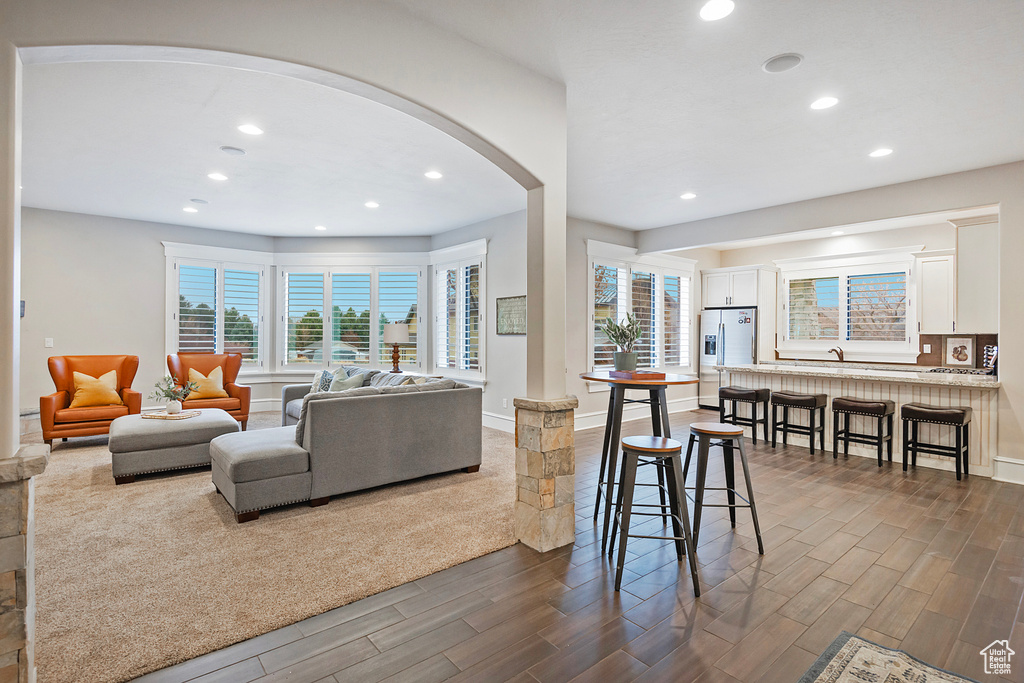 Living room with dark wood finished floors, arched walkways, healthy amount of natural light, recessed lighting, and baseboards