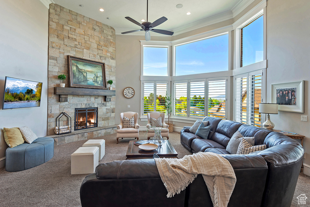 Living room featuring carpet flooring, ornamental molding, a ceiling fan, a towering ceiling, and baseboards