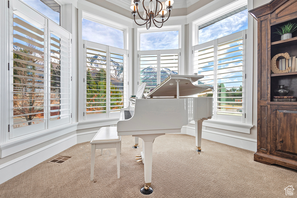 Sitting room featuring carpet, healthy amount of natural light, a chandelier, and crown molding
