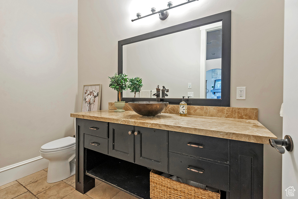 Bathroom featuring toilet, vanity, baseboards, and tile patterned floors