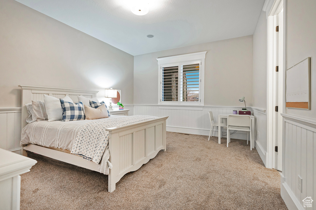 Bedroom with wainscoting and light colored carpet