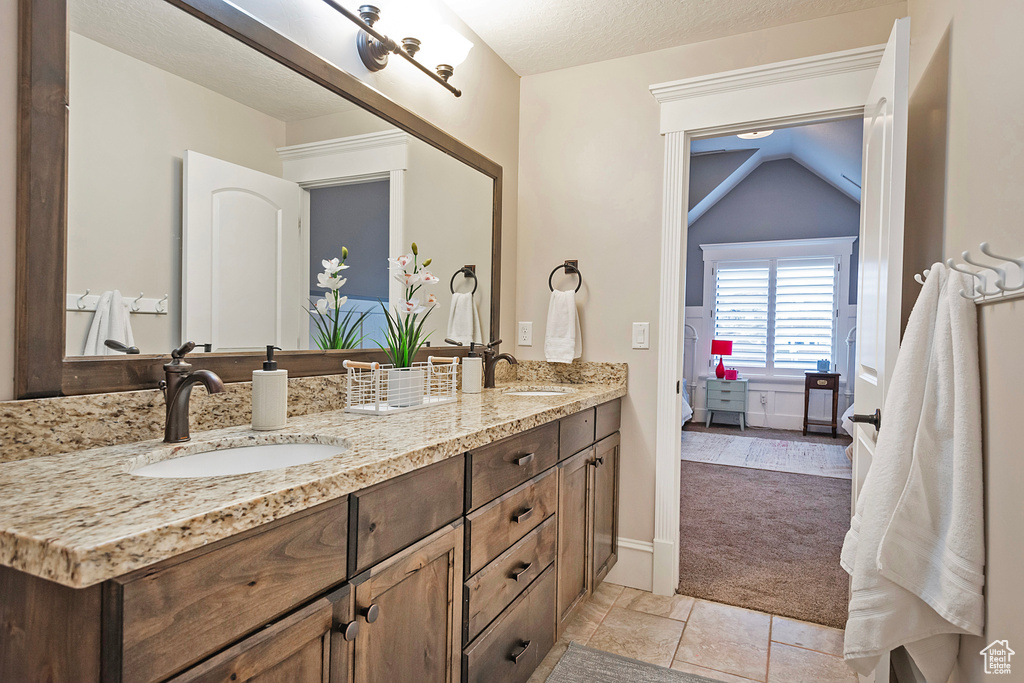Full bathroom featuring double vanity, connected bathroom, and lofted ceiling