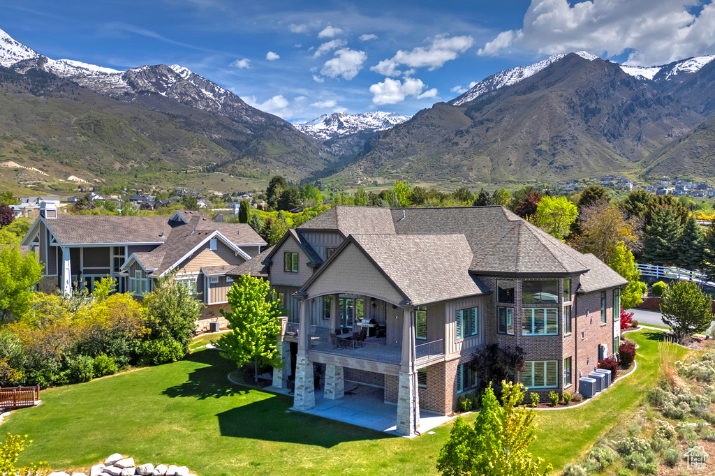 Back of house with a patio area, a lawn, central AC, and a mountain view