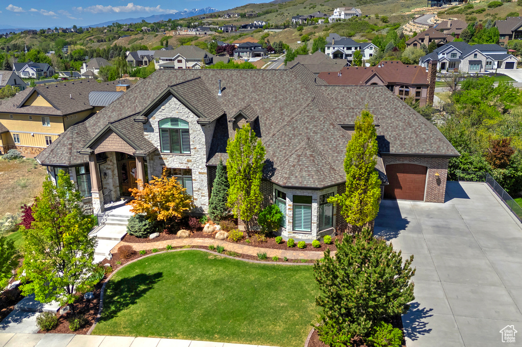 French country inspired facade with stone siding, driveway, a residential view, a garage, and a front yard