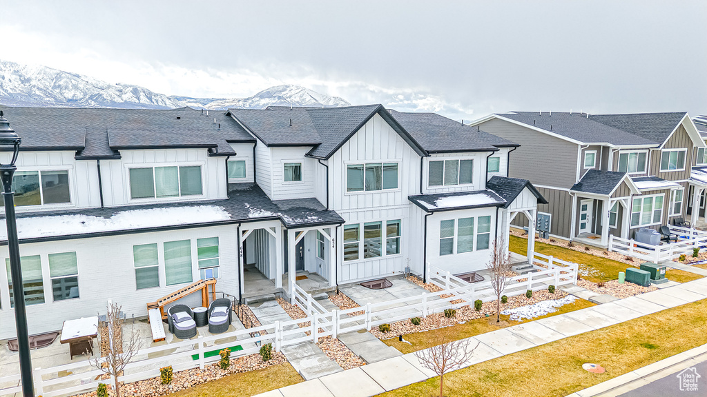 Townhome / multi-family property with fence, a mountain view, a residential view, board and batten siding, and a shingled roof