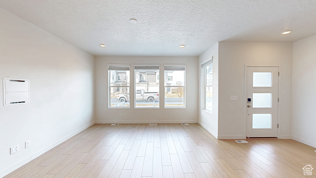 Foyer entrance with recessed lighting, light wood-type flooring, baseboards, and a textured ceiling