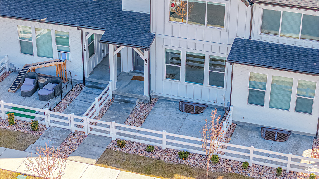 Property entrance with fence, board and batten siding, and a shingled roof