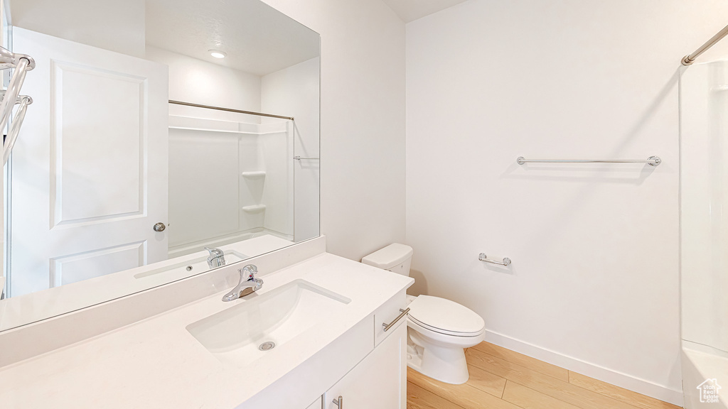 Full bathroom with baseboards, toilet, wood finished floors, and vanity