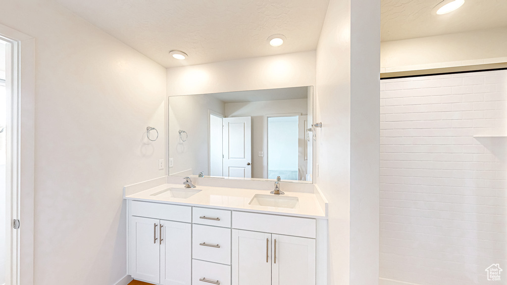 Full bathroom featuring double vanity, recessed lighting, a shower, and a sink