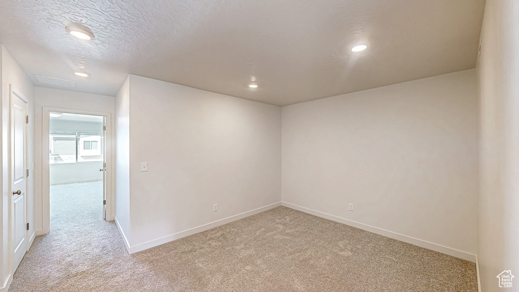 Empty room featuring recessed lighting, baseboards, light colored carpet, and a textured ceiling