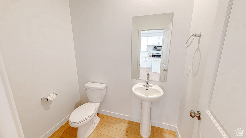 Half bath with toilet, wood finished floors, and baseboards