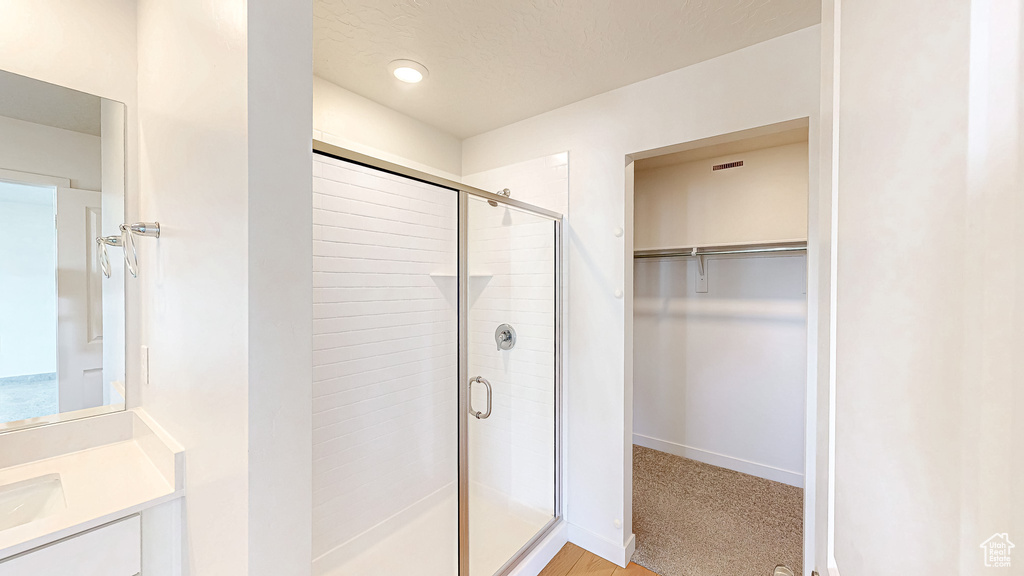 Full bath with a walk in closet, baseboards, a stall shower, and vanity