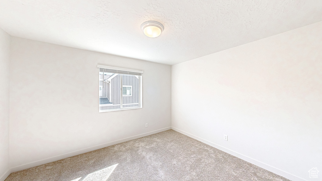 Carpeted empty room featuring baseboards and a textured ceiling