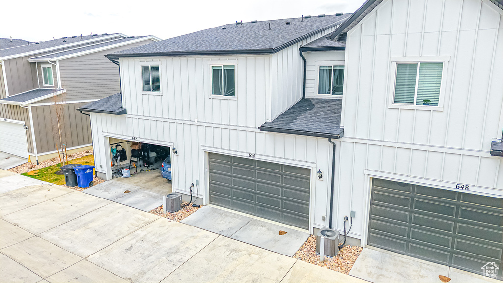 Rear view of house featuring concrete driveway, an attached garage, board and batten siding, and roof with shingles