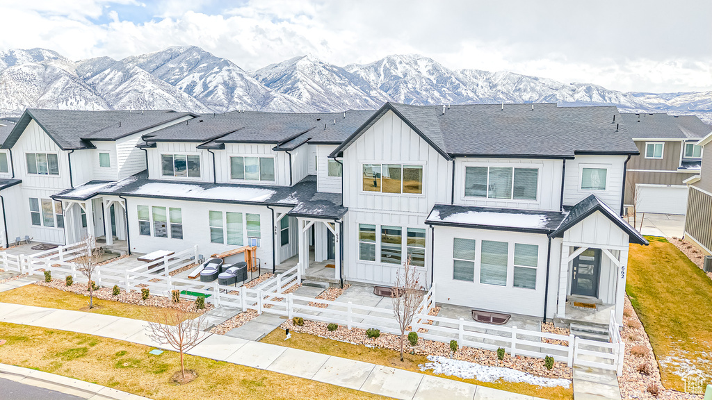 View of property featuring a mountain view, a residential view, board and batten siding, a shingled roof, and fence private yard