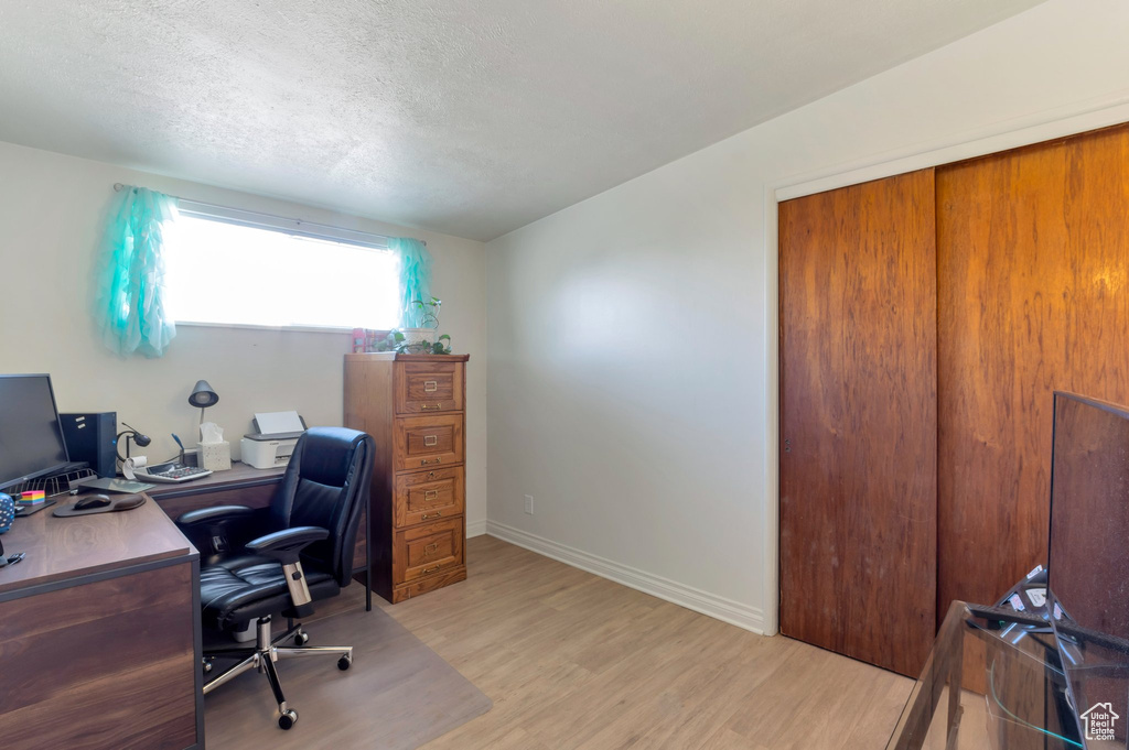 Office space with light wood-style flooring, a textured ceiling, and baseboards