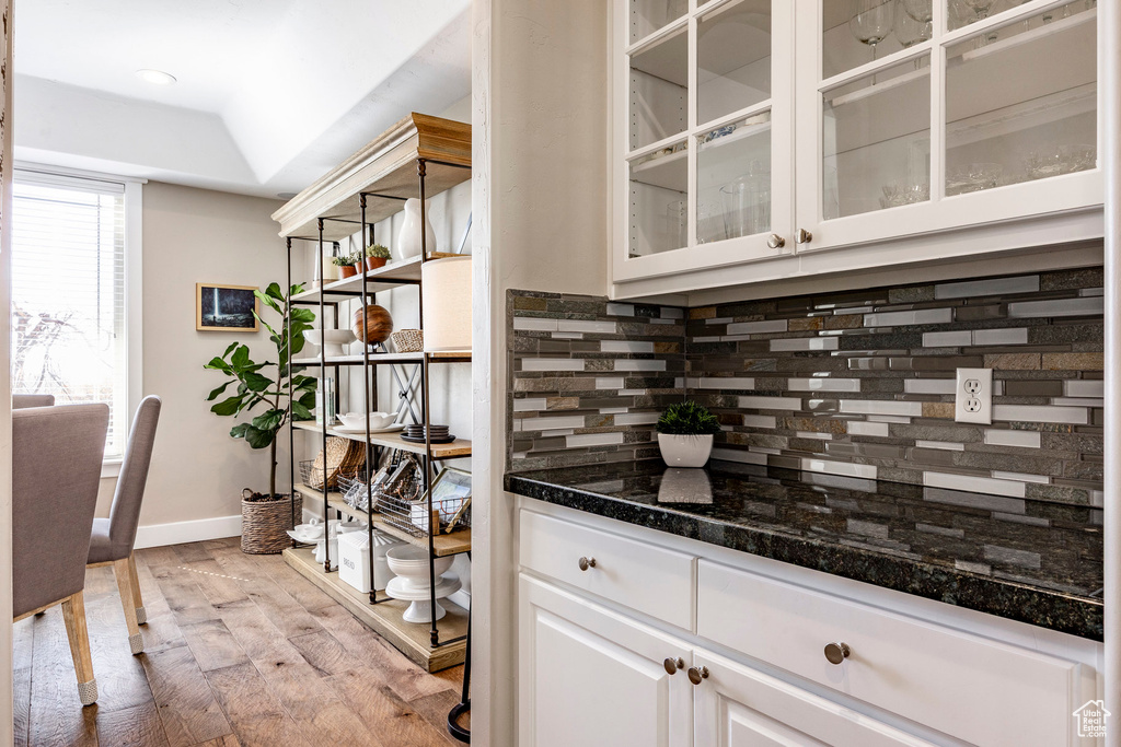 Bar featuring tasteful backsplash, light wood-type flooring, and baseboards