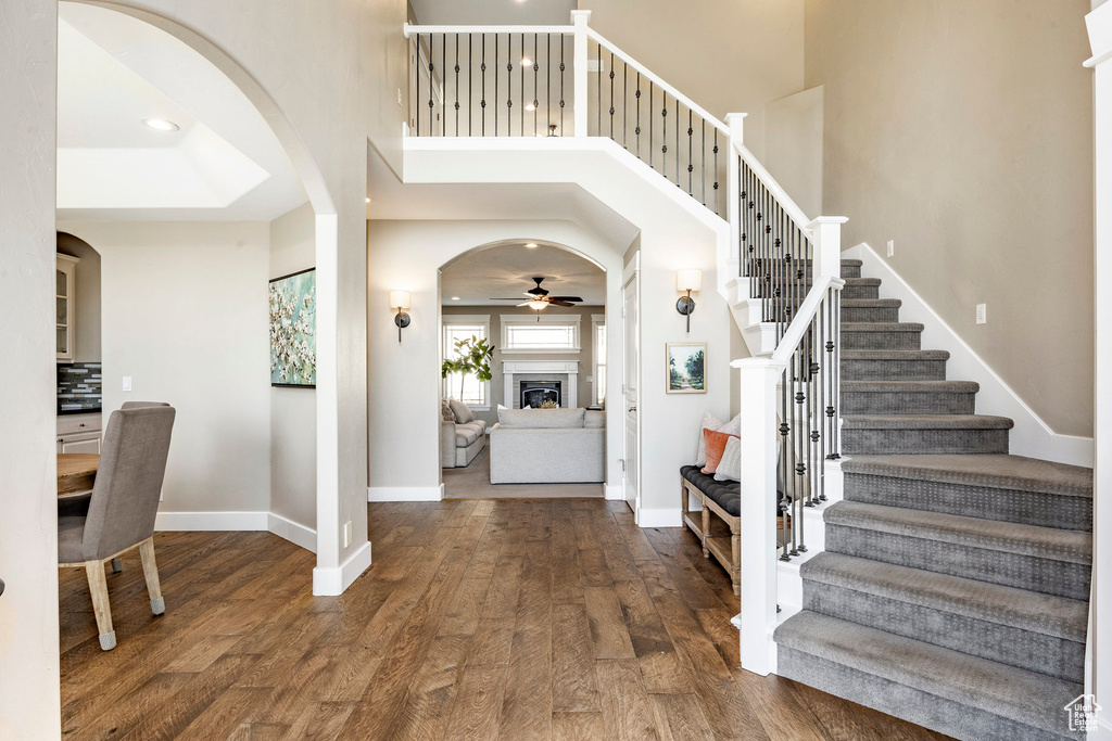 Entrance foyer featuring arched walkways, ceiling fan, wood finished floors, baseboards, and a high ceiling
