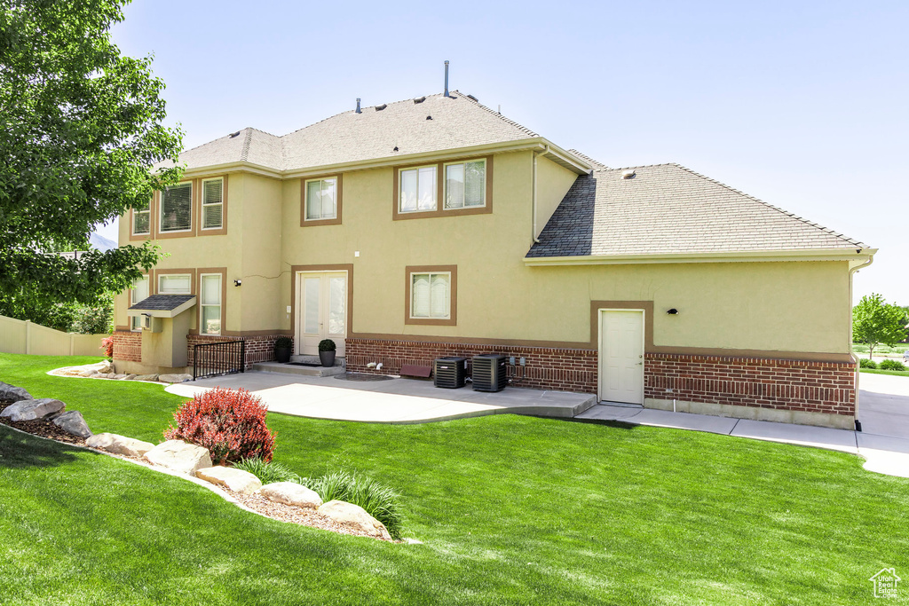 Back of house with stucco siding, a patio area, central air condition unit, and brick siding