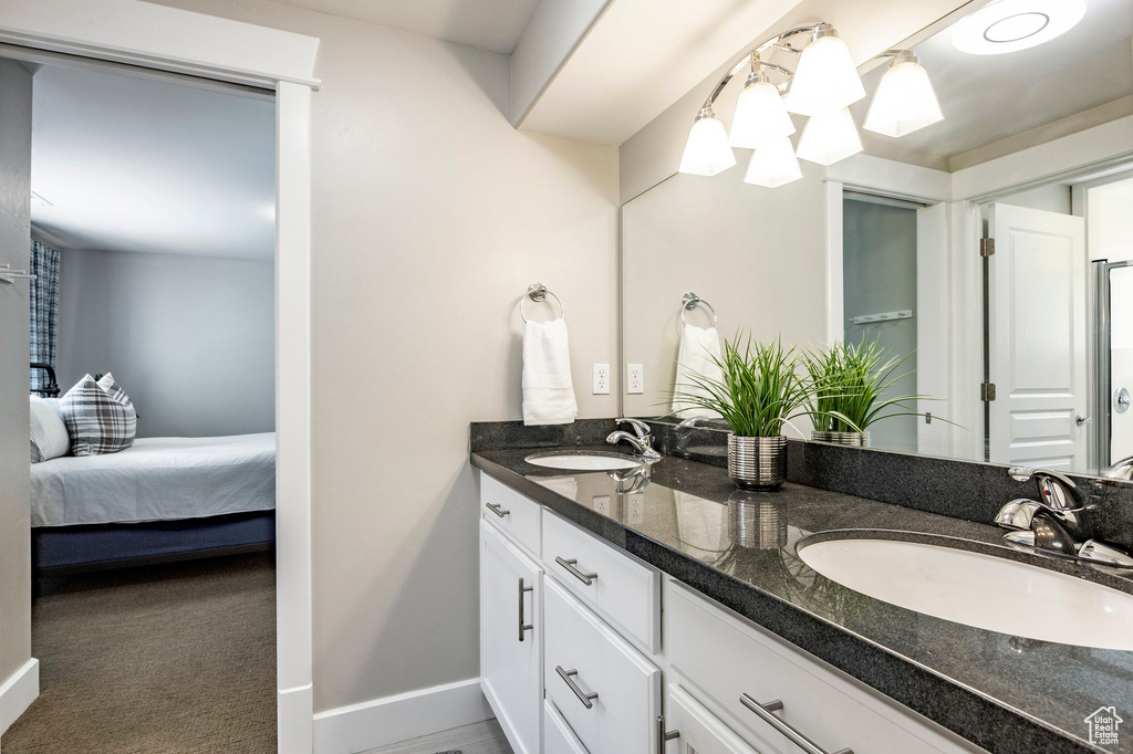 Full bathroom featuring double vanity, ensuite bath, and baseboards