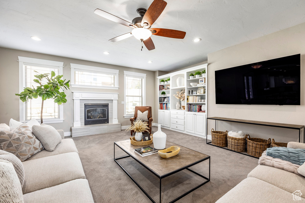 Living room with a glass covered fireplace, light carpet, a ceiling fan, recessed lighting, and baseboards