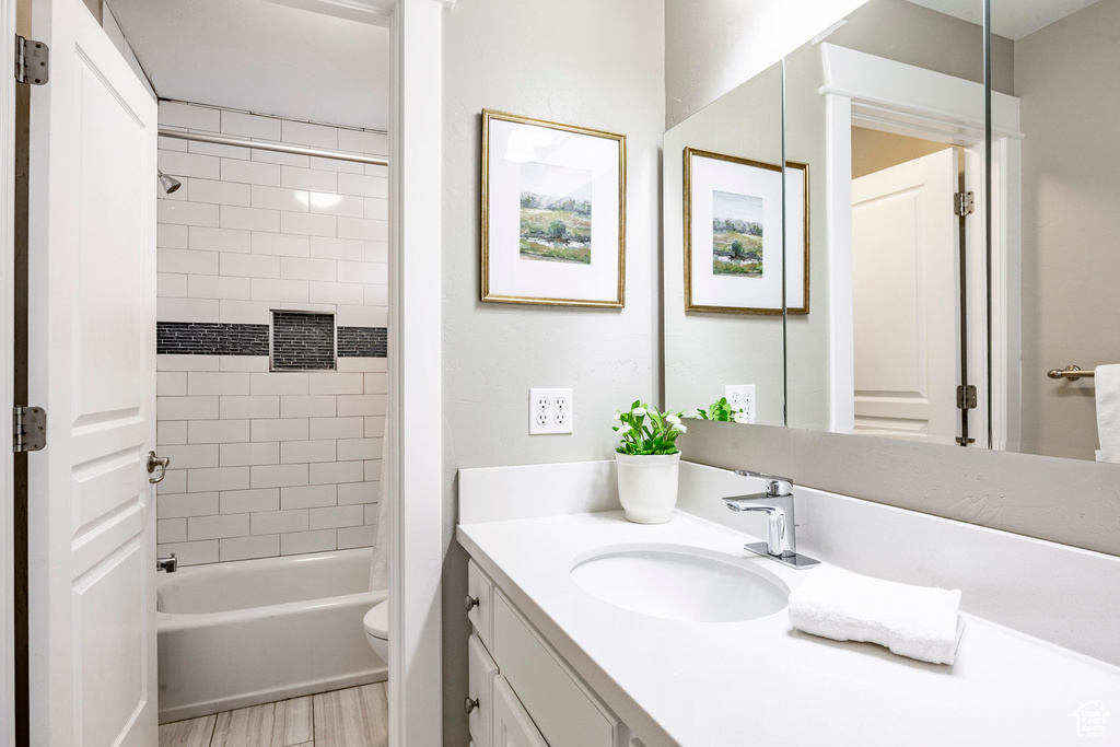 Bathroom featuring vanity, toilet, shower / bathtub combination, and wood finished floors