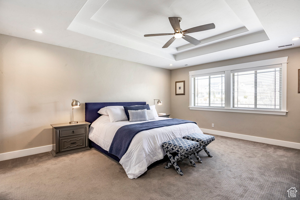 Bedroom with a raised ceiling, light carpet, baseboards, and recessed lighting