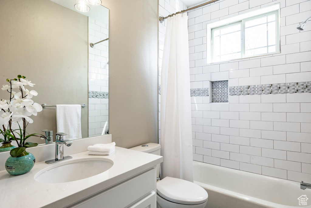 Bathroom featuring vanity, toilet, and shower / tub combo with curtain