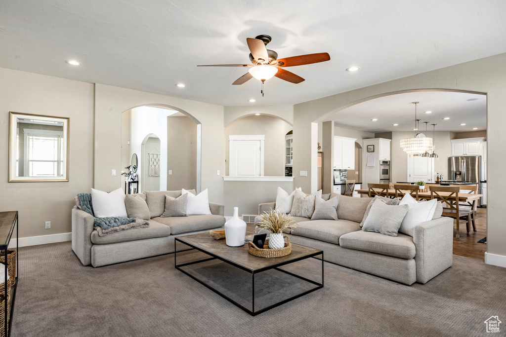 Living area featuring recessed lighting, a ceiling fan, carpet, baseboards, and arched walkways