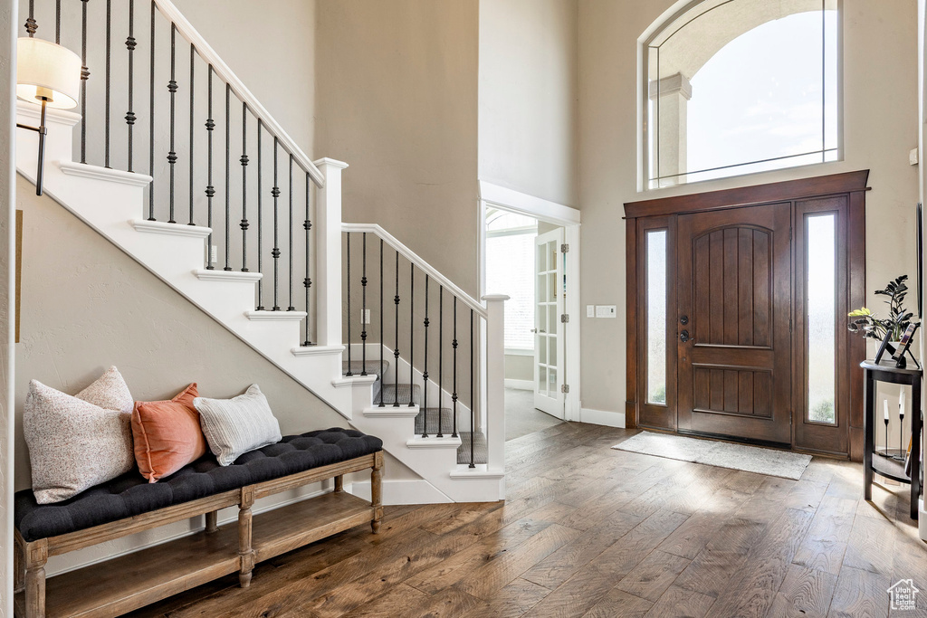 Entryway featuring a high ceiling, hardwood / wood-style floors, healthy amount of natural light, and stairway