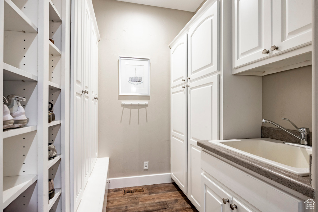 Washroom with a sink, dark wood-style flooring, and baseboards