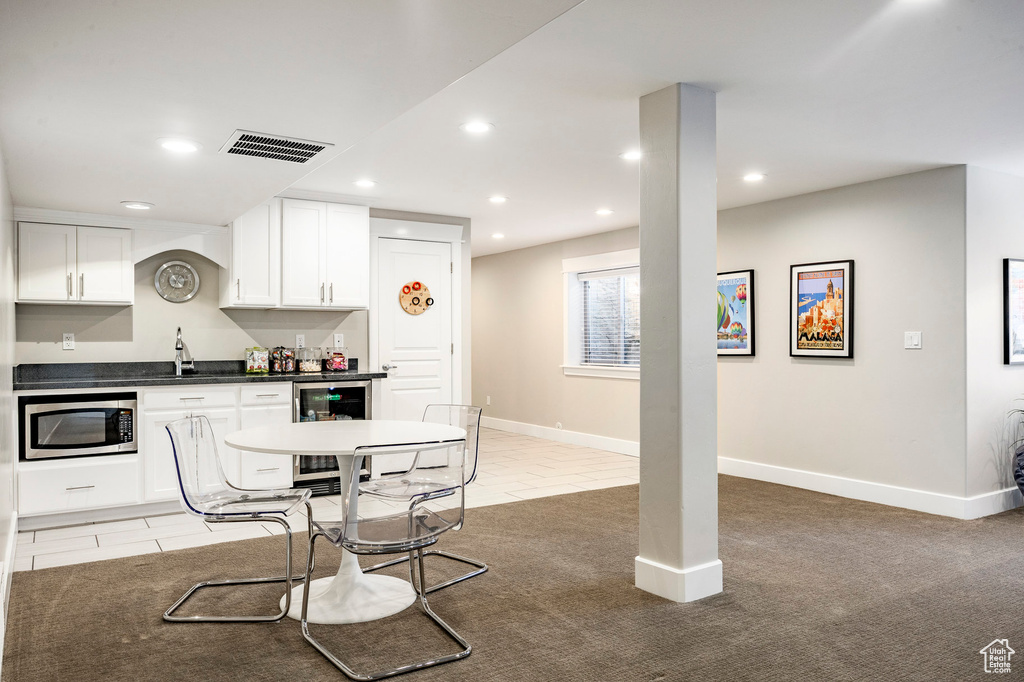 Kitchen featuring stainless steel microwave, dark countertops, white cabinetry, recessed lighting, and wine cooler