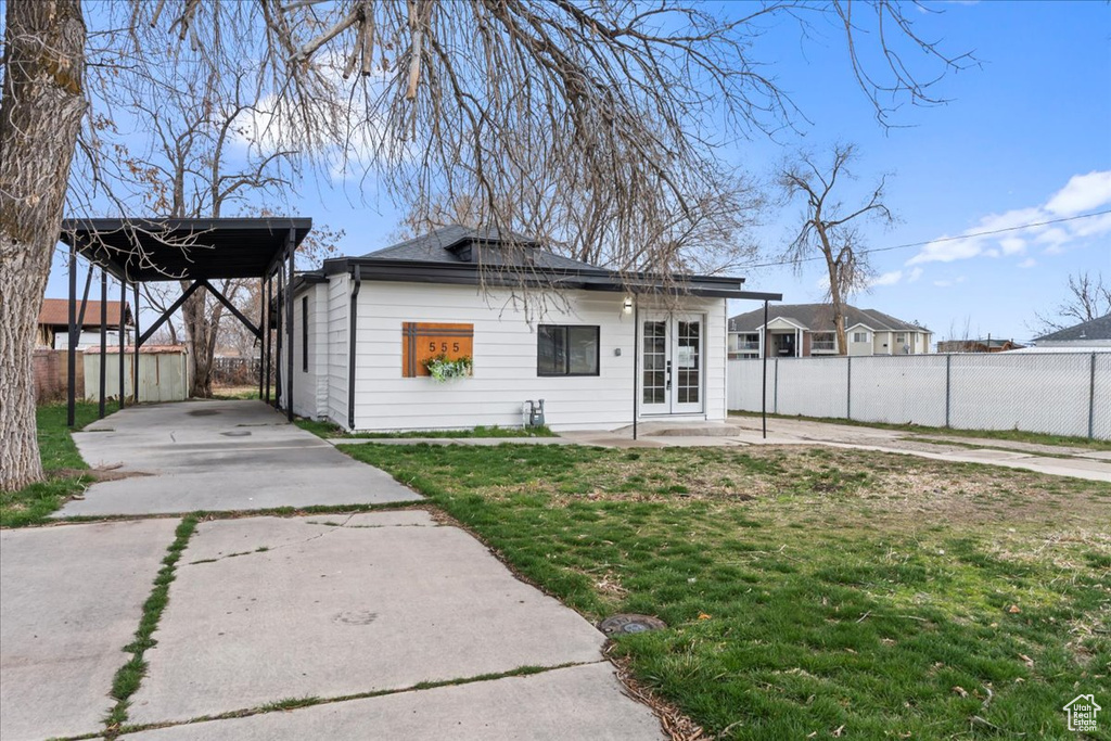 Back of house featuring french doors, a yard, concrete driveway, and fence