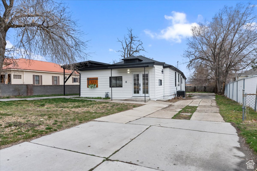 Back of property featuring driveway, french doors, fence, and central AC