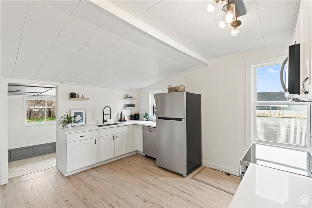 Kitchen featuring a sink, light countertops, lofted ceiling, stainless steel appliances, and open shelves