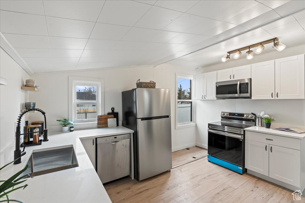 Kitchen featuring a sink, light countertops, white cabinets, light wood-style floors, and appliances with stainless steel finishes