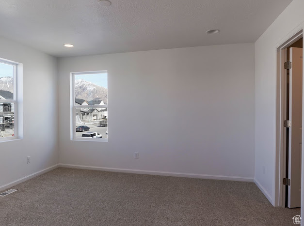 Carpeted empty room featuring baseboards and recessed lighting