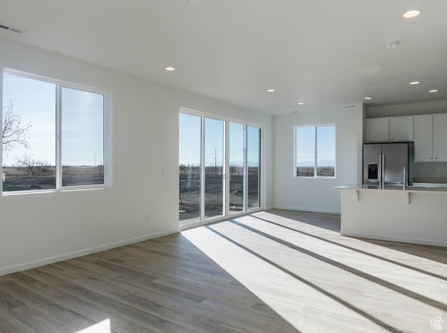 Unfurnished living room featuring recessed lighting, baseboards, and wood finished floors