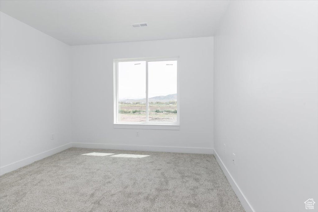 Empty room with visible vents, carpet, and baseboards