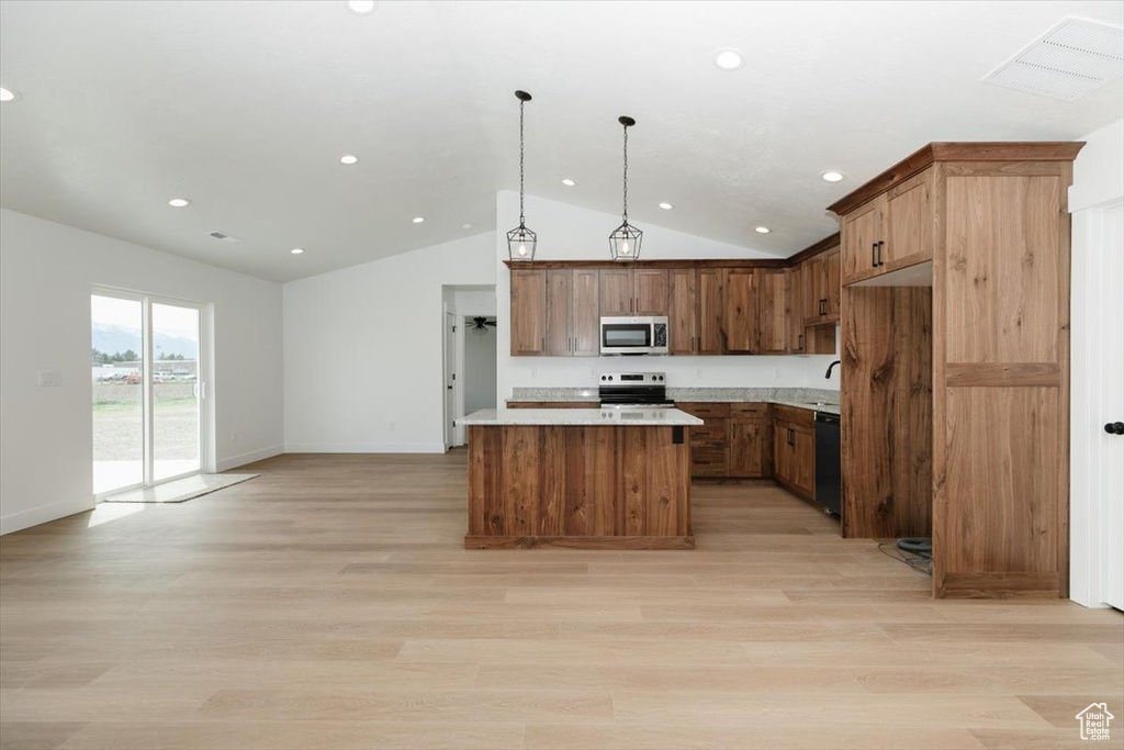 Kitchen with a kitchen island, appliances with stainless steel finishes, open floor plan, light wood-style floors, and lofted ceiling