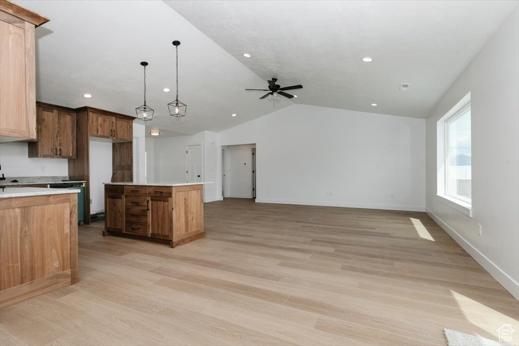 Kitchen featuring a kitchen island, light wood-type flooring, light countertops, a ceiling fan, and vaulted ceiling
