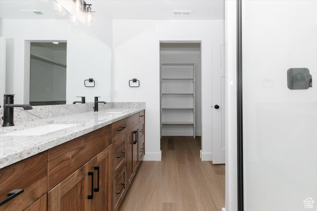 Full bathroom featuring double vanity, visible vents, a sink, and wood finished floors