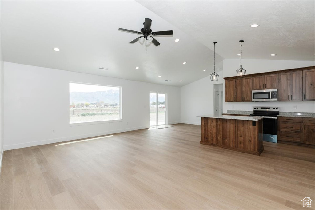 Kitchen featuring appliances with stainless steel finishes, recessed lighting, open floor plan, a kitchen island, and vaulted ceiling