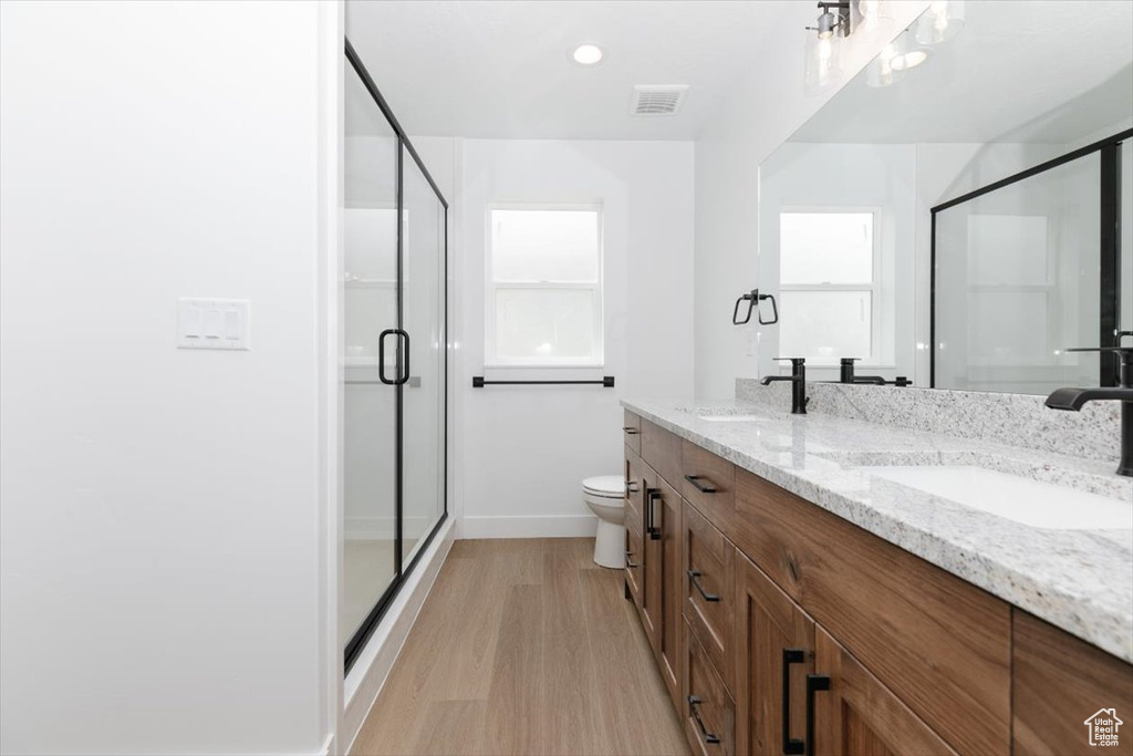 Bathroom with baseboards, a shower stall, a sink, and wood finished floors
