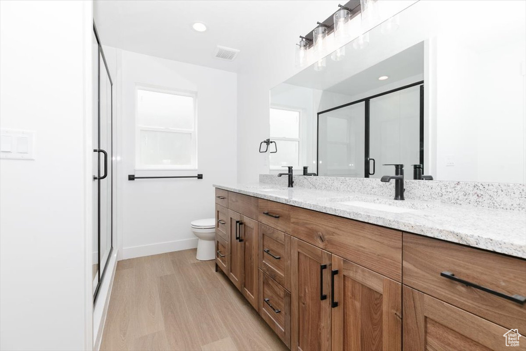 Bathroom with double vanity, visible vents, a stall shower, a sink, and baseboards